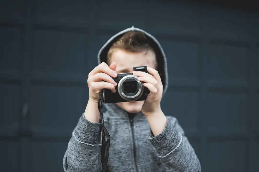 person in grey hoodie holding up camera over face
