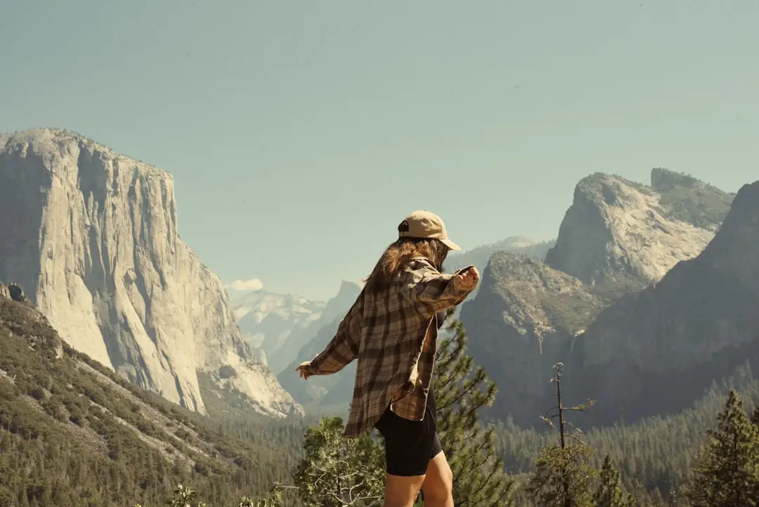 Woman in flannel overlooks yosemite valley mountains