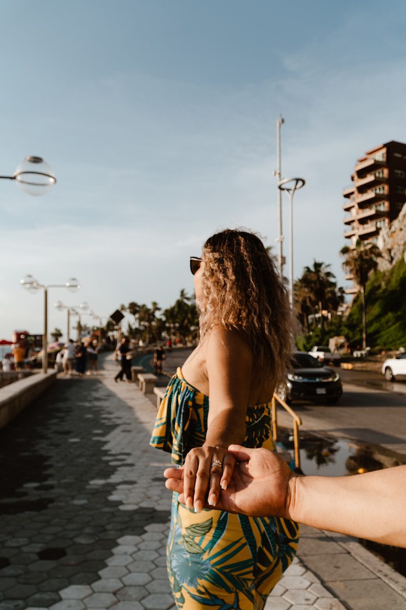 Woman holding hand while walking by the ocean.